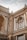 A detailed architectural structure featuring classic and ornate decorative elements, including columns, arched windows, and intricate carvings on a facade. The building exhibits a historic and elegant design with light beige and brown tones.