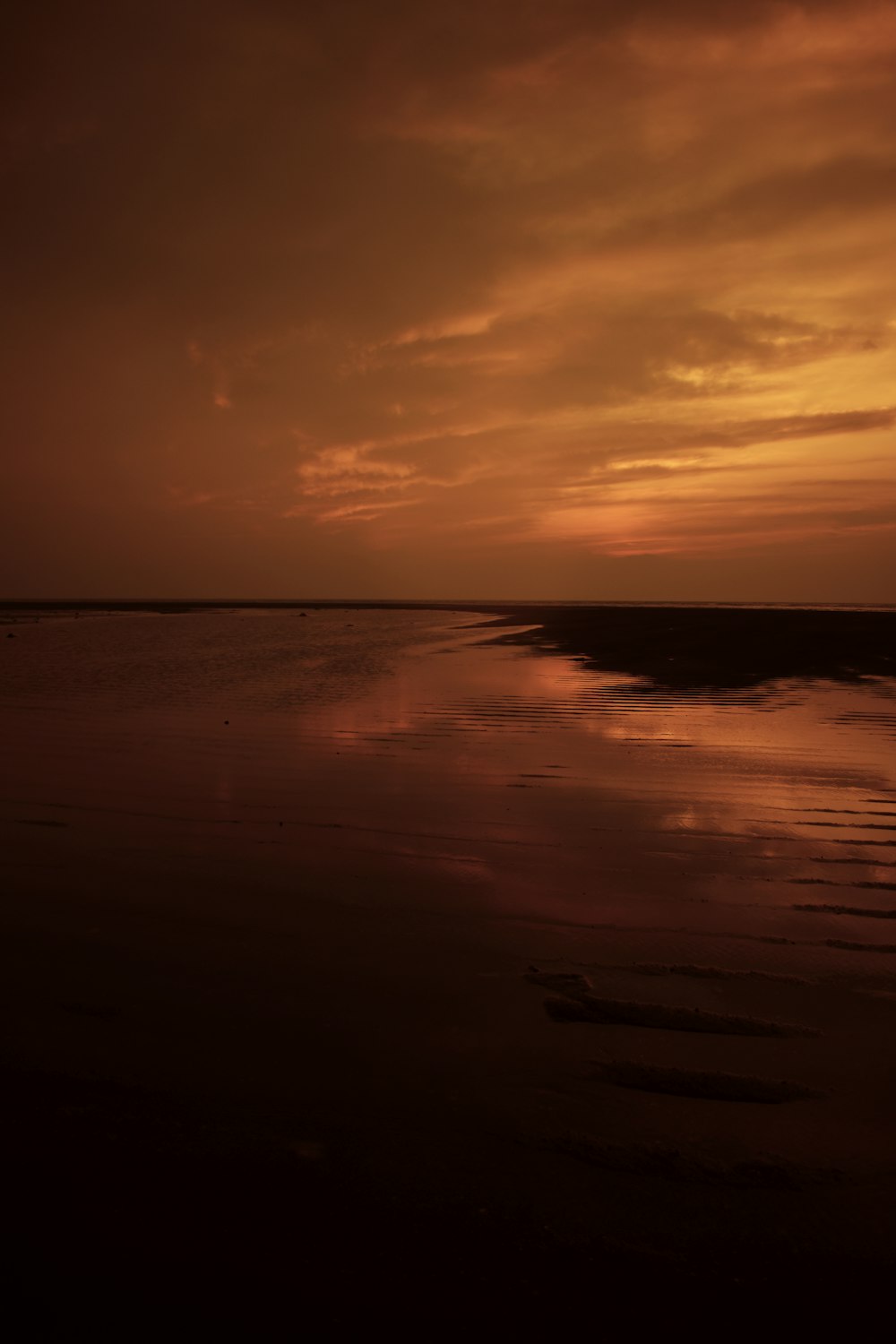 the sun is setting over the water on the beach