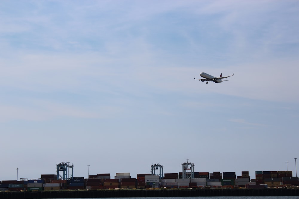 an airplane is flying over a cargo dock