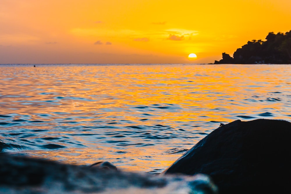 a sunset over a body of water with a small island in the distance