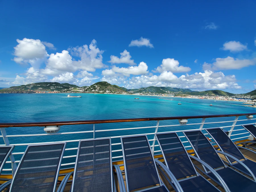 Empty sun loungers on a cruise deck overlooking a turquoise Caribbean bay
