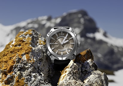 macro photography of round silver-colored and brown chronograph watch on stones