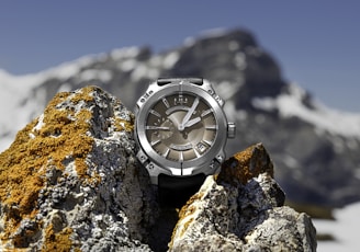 macro photography of round silver-colored and brown chronograph watch on stones