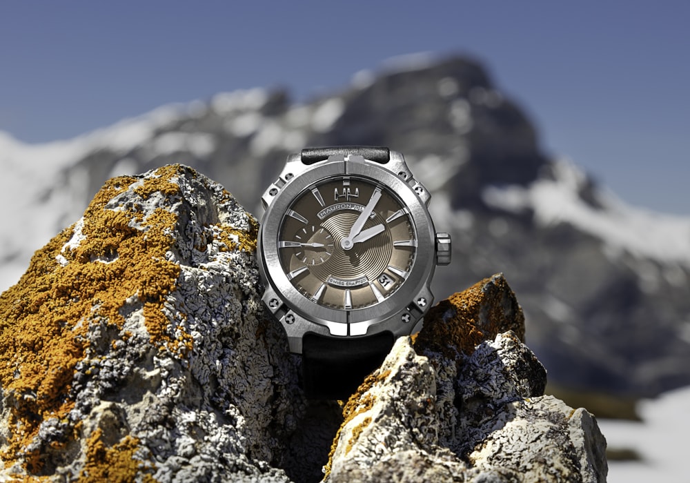 macro photography of round silver-colored and brown chronograph watch on stones