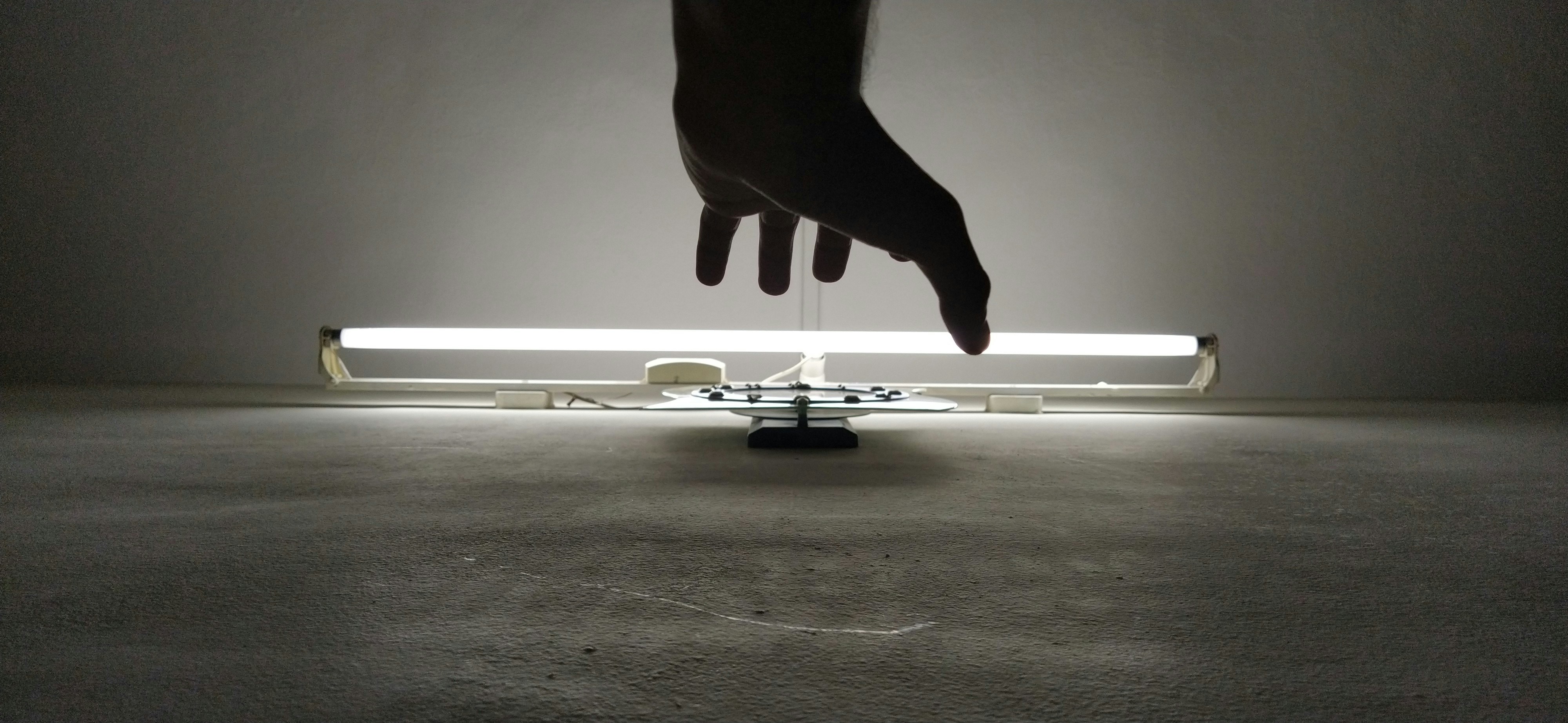 silhouette of person's hand near fluorescent lamp