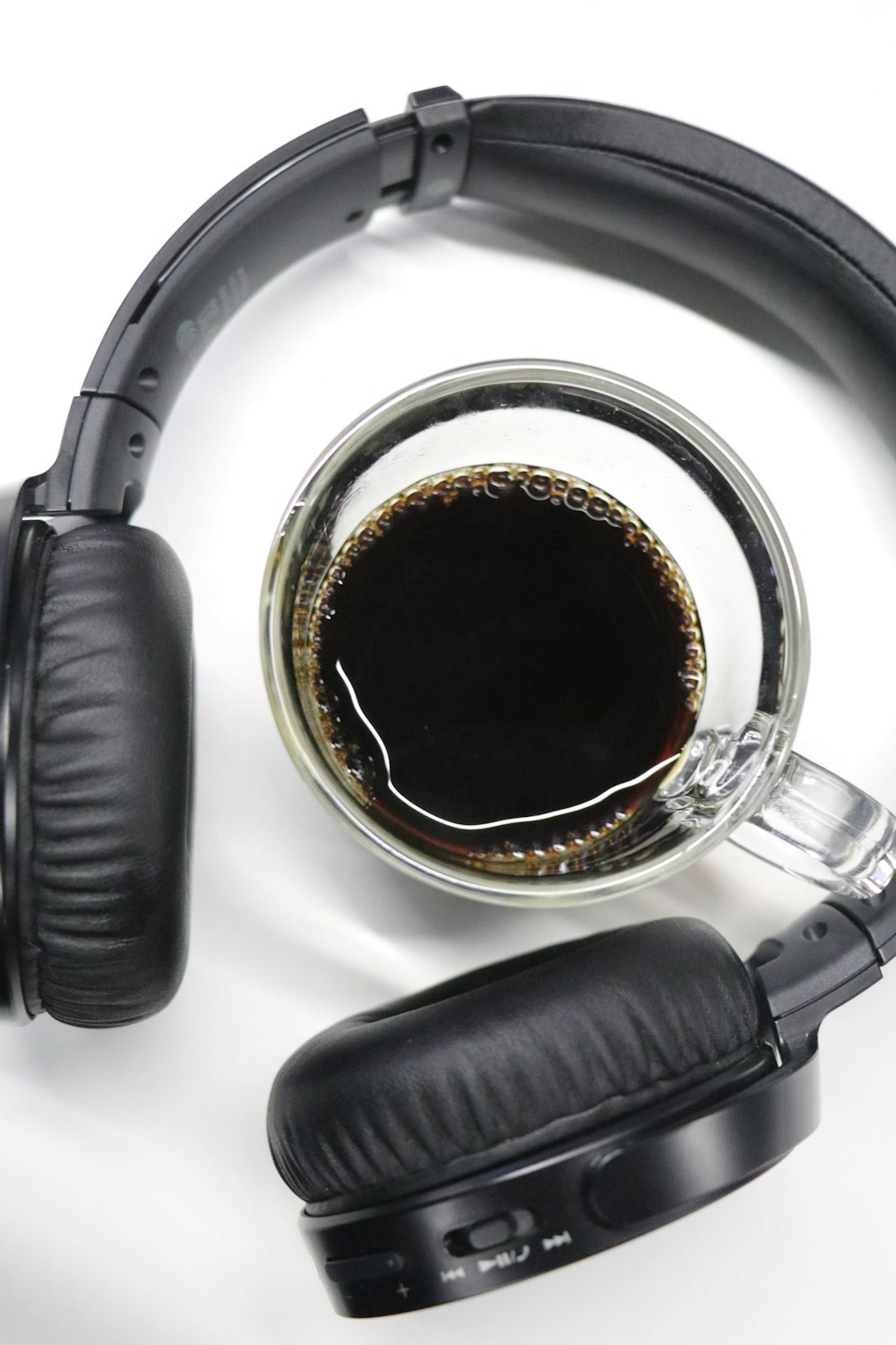 half-filled clear glass cup in black wireless headphones