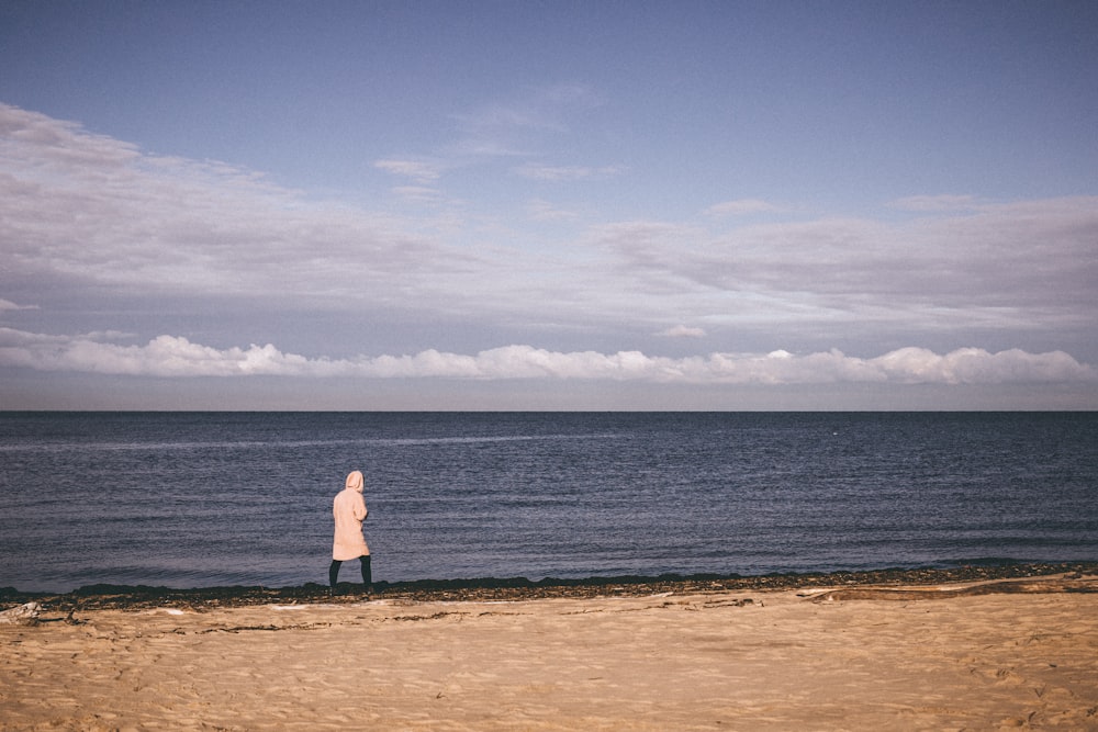 person standing on shoreline facing the beach