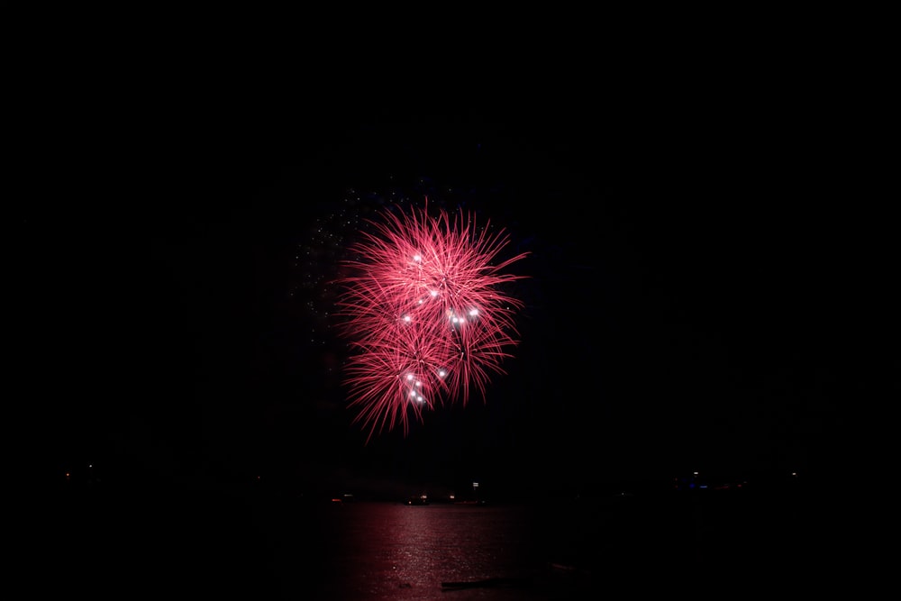 low-light photography and in distant photo of red fireworks