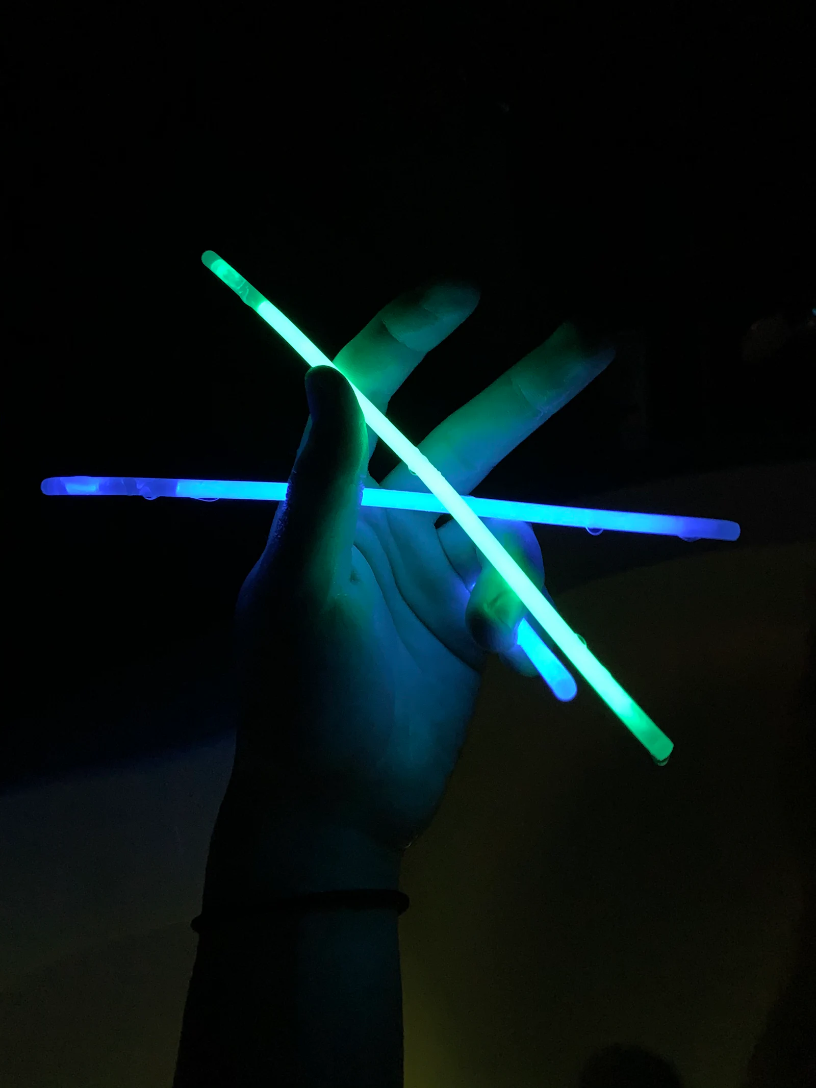 A pair of glow sticks held up in the dark.