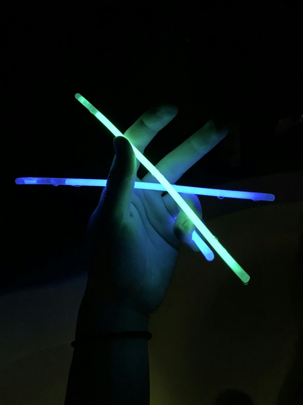 a person holding two glowing sticks in the dark