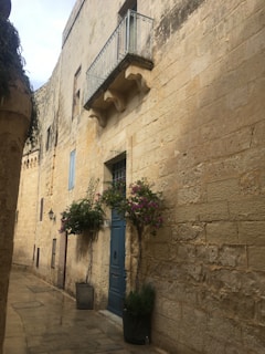 Cozy apartment balcony with vibrant flowers in a narrow Italian street.