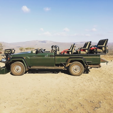 A welcoming safari guide standing next to a vintage 4x4 jeep in the golden light of sunrise on the savannah.