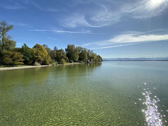 A serene lakeside view with reflections of golden trees and a clear sky.