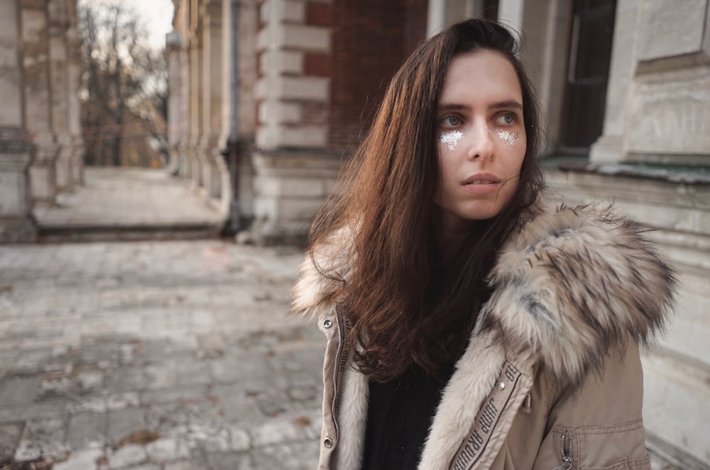 woman in gray winter jacket standing near concrete building during daytime