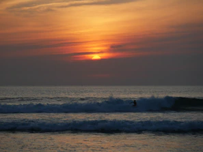 Sunset surf session at a quiet California beach with vibrant orange skies