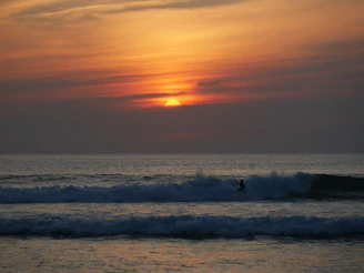 Sunset surf session at a quiet California beach with vibrant orange skies