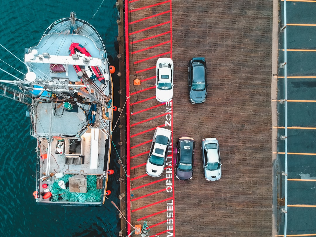 aerial photography of five buildings on road viewing boat on body of water during daytime