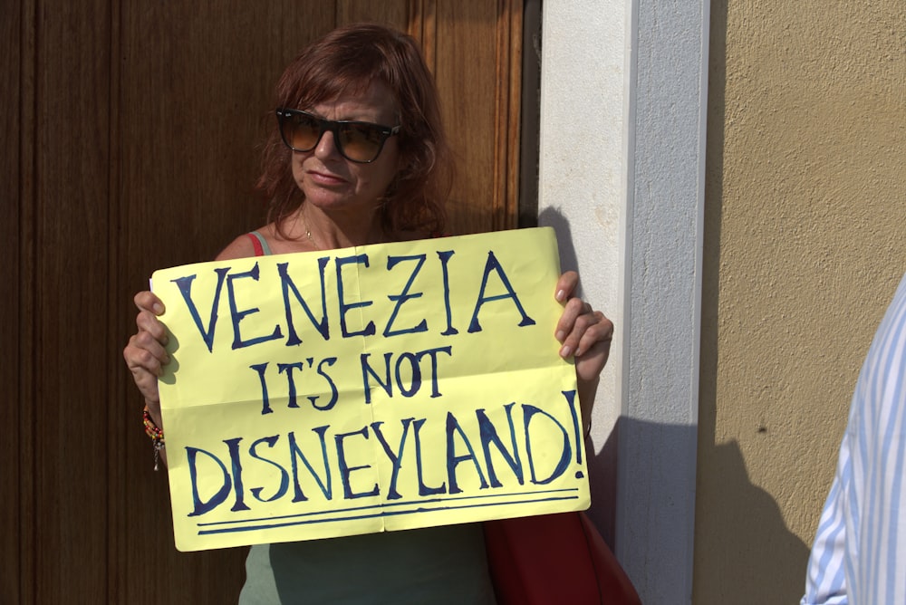 woman holding Venezia it's not Disneyland placard