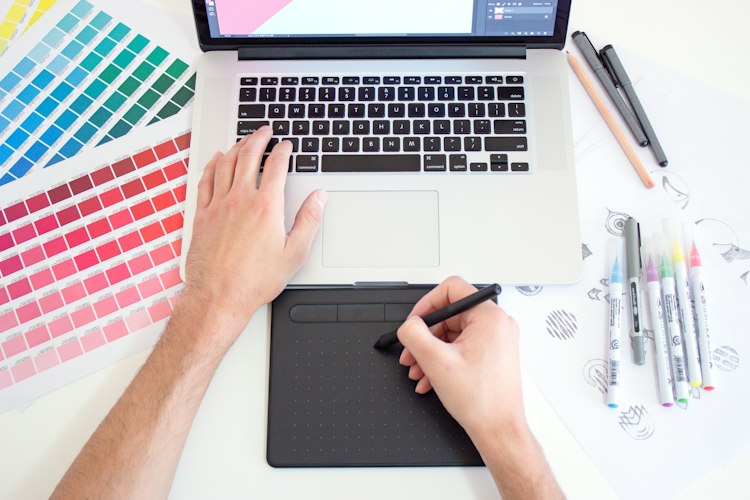 Digital artist working on character design at a computer with a graphics tablet