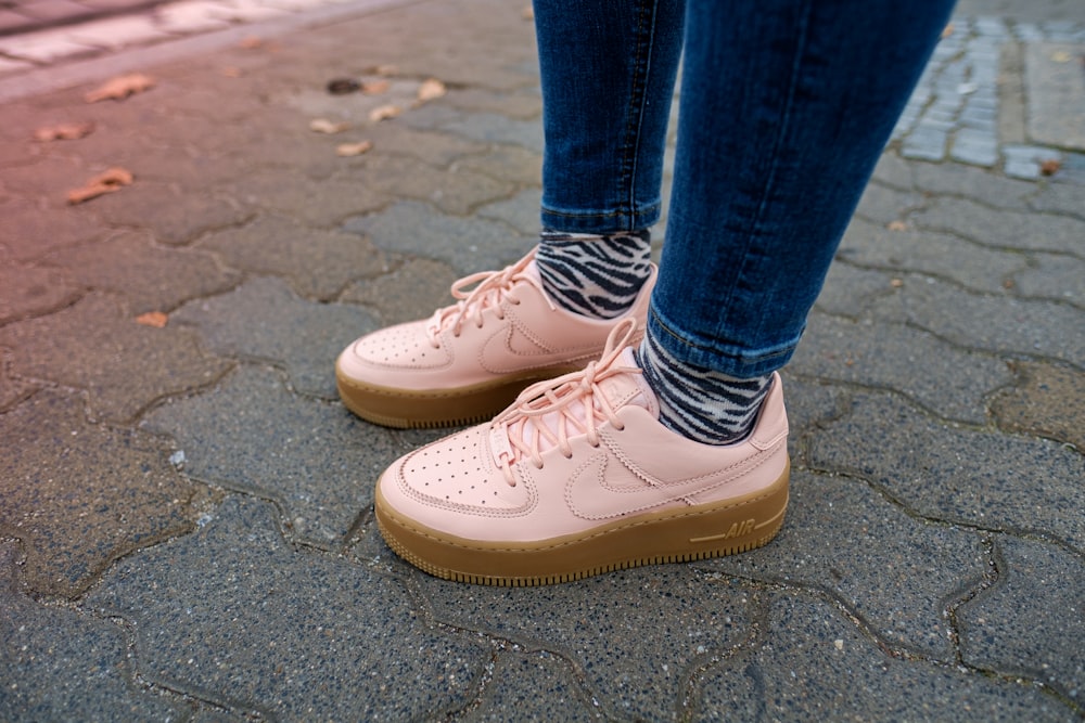 person wearing blue denim jeans and white Nike Air Force low-top sneakers standing