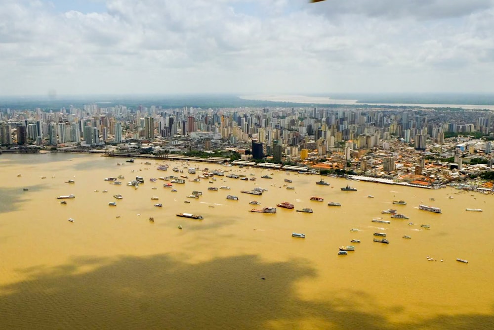 aerial photography of city with high-rise buildings viewing boats on sea under white and blue sky during daytime