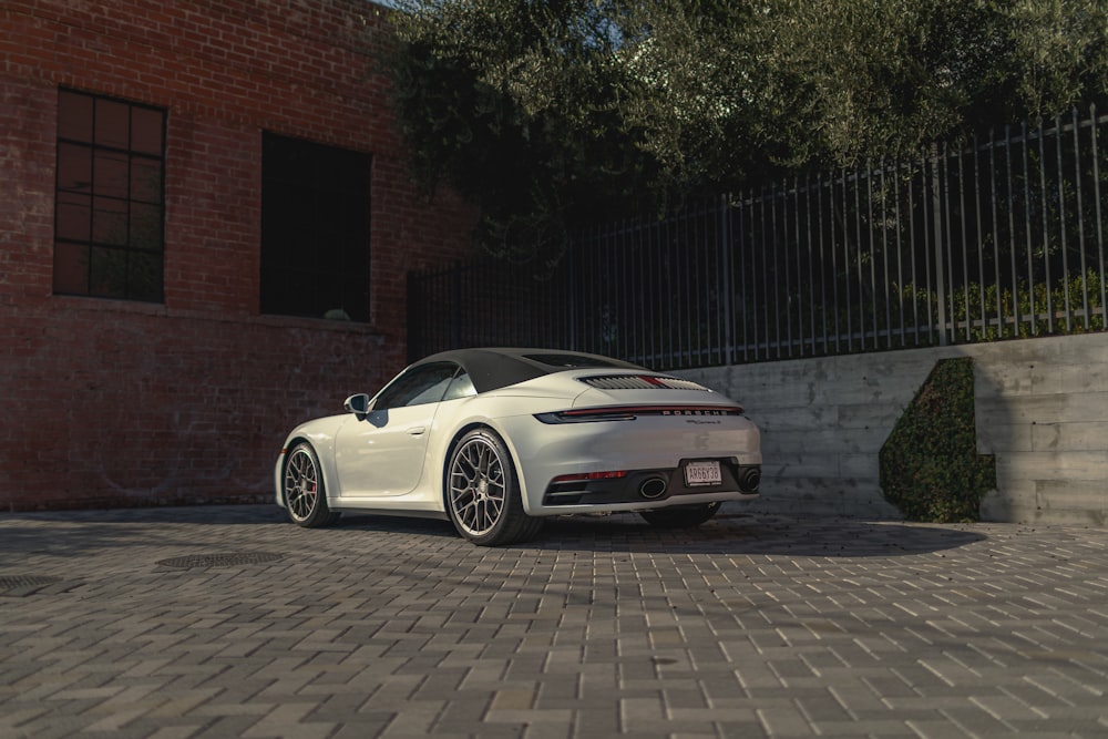 white Porsche convertible coupe parked beside wall