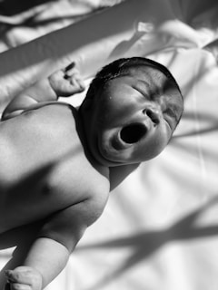 grayscale photo of baby on bed