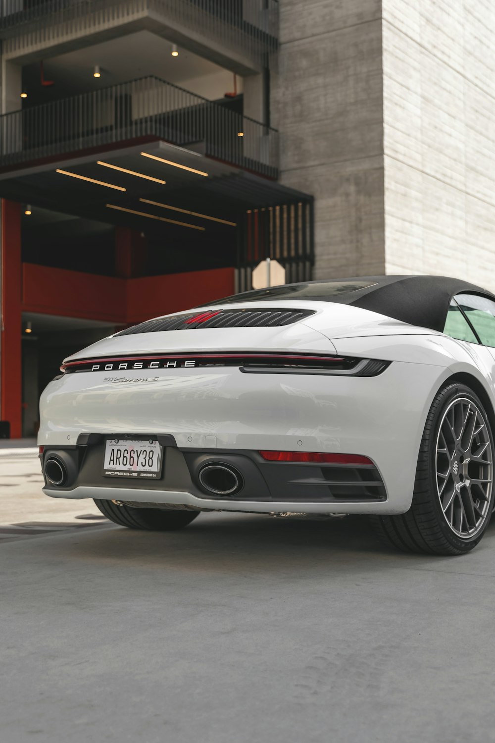 Vehículo Porsche blanco junto a un edificio gris durante el día