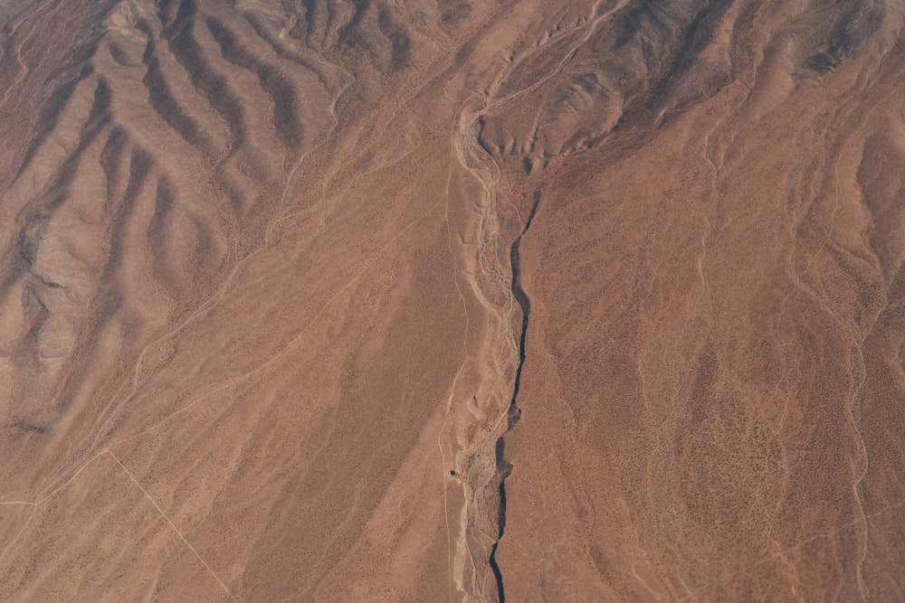 an aerial view of a desert with a plane flying over it