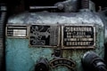 A close-up view of an industrial machine panel with various Chinese characters and numerical labels. The surface displays wear and crackling paint, suggesting age and use. There are two metal plates with technical diagrams and descriptions, along with numbers and letters in white on a black background.
