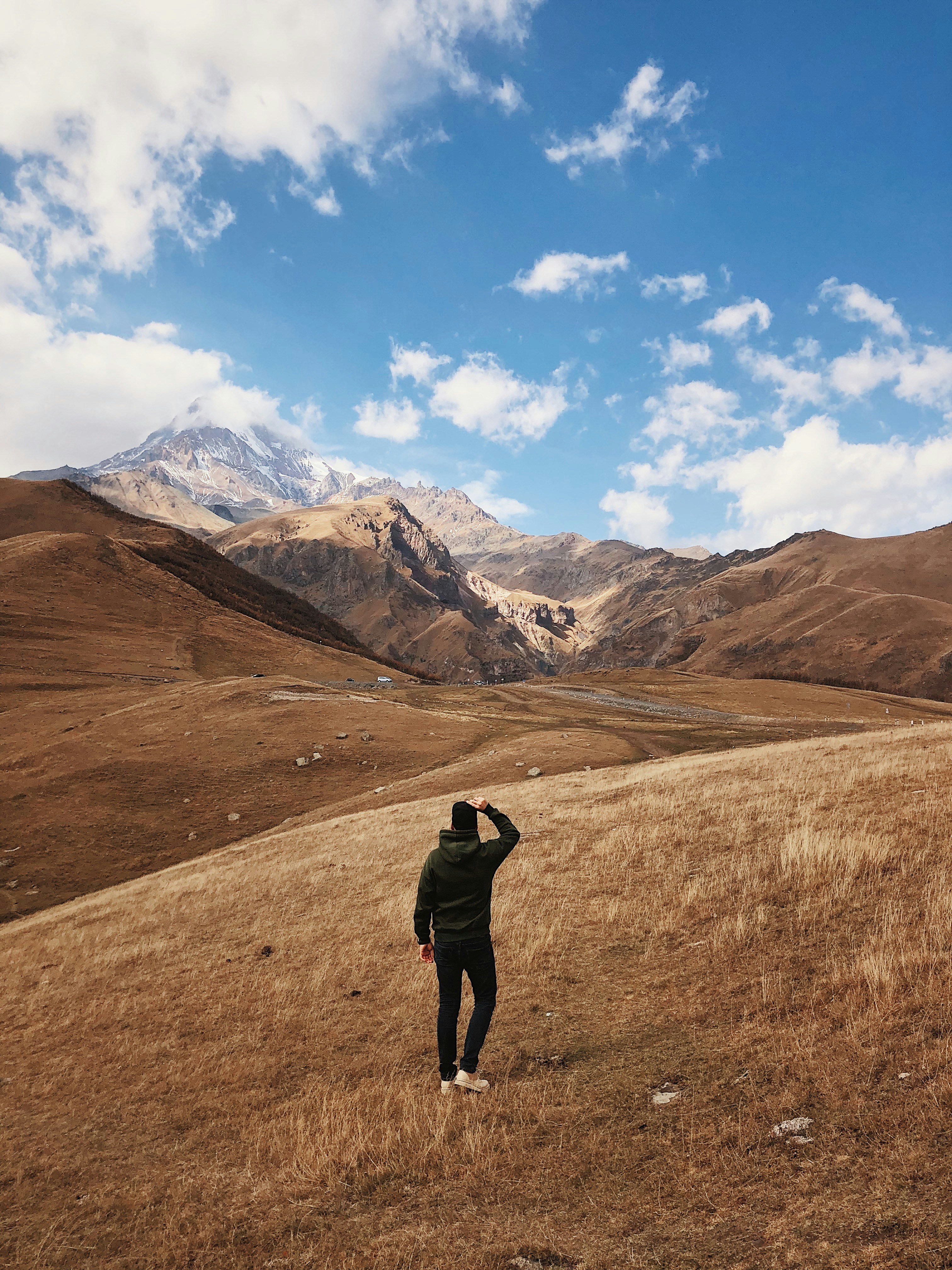 man in hoodie walking on hill