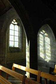 A peaceful church interior with sunlight filtering through stained glass windows, creating colorful patterns.