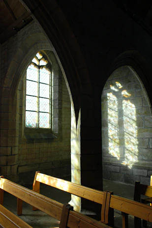 Sunlight streaming through stained glass windows inside a peaceful church sanctuary.