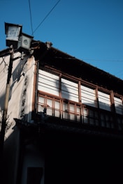 Volunteers carefully restoring a historic building’s wooden window frame under bright daylight.