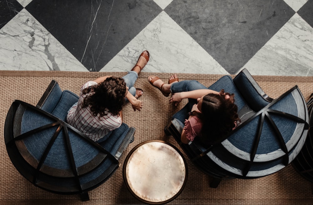 two women sitting on blue armchairs