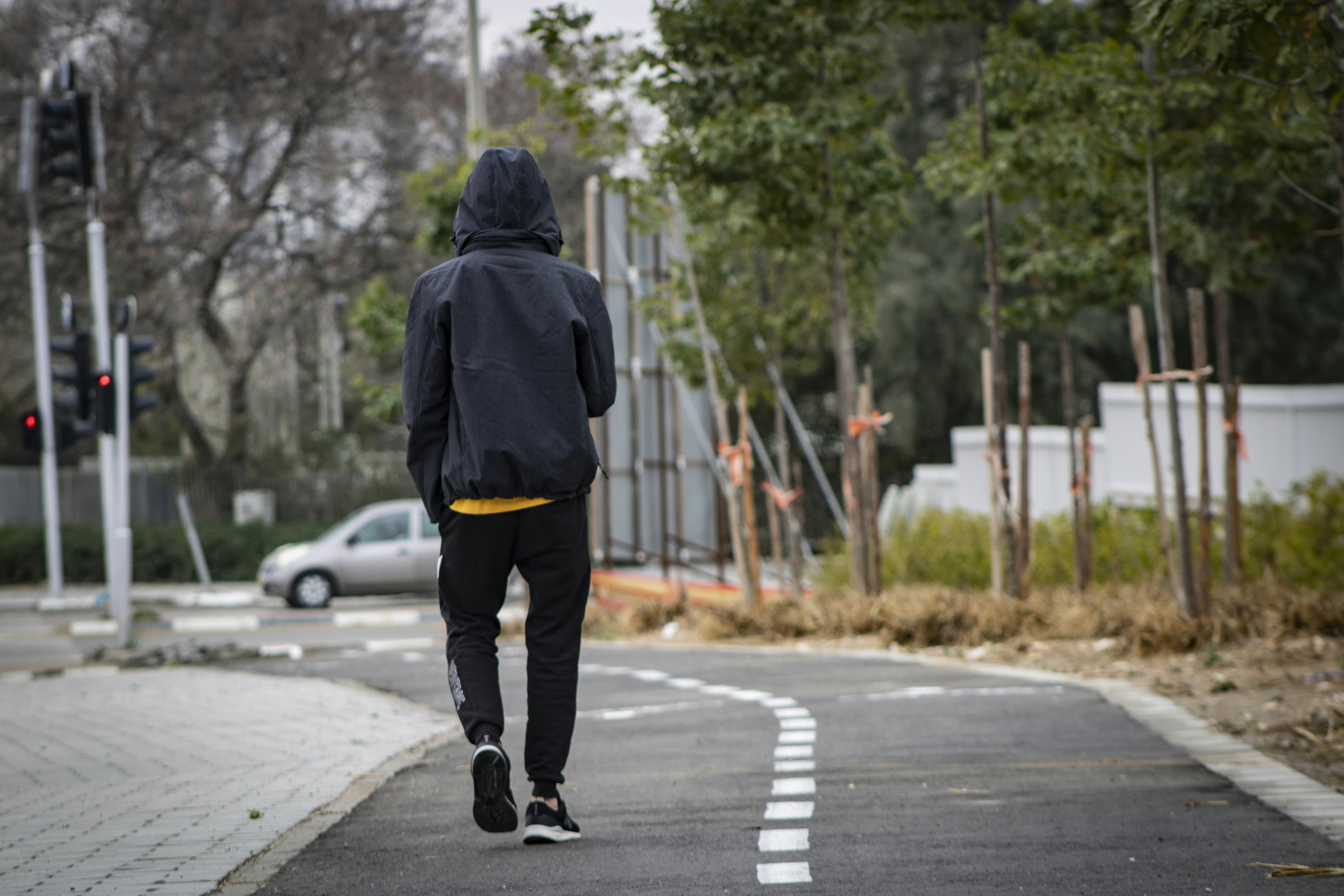 Young man in black jacket walking down street