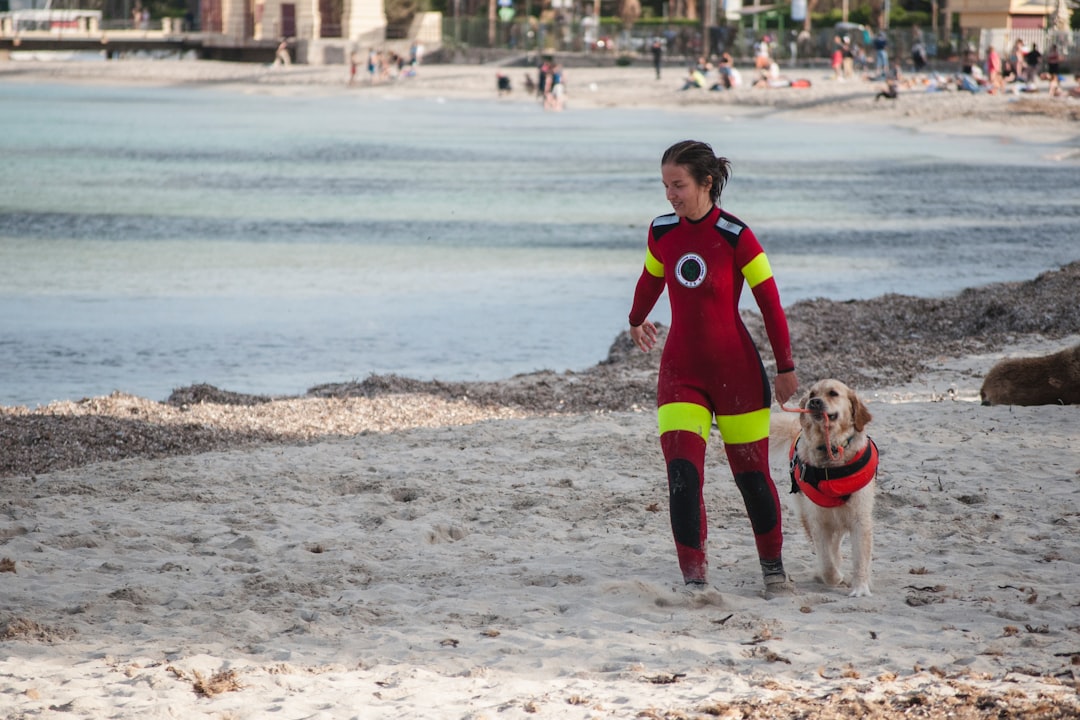 woman in red jumpsuit beside brown dog