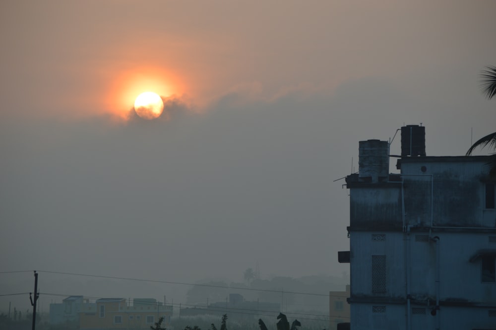 the sun is setting over a city in the fog