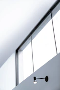 A sleek black aluminum window framed by a modern white wall under bright sunlight.