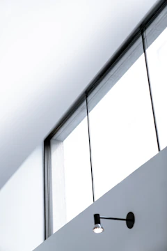 A sleek black aluminum window framed by a modern white wall under bright sunlight.