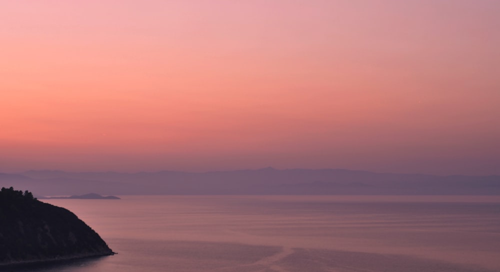 Gewässer mit Blick auf den Berg unter orangefarbenem Himmel