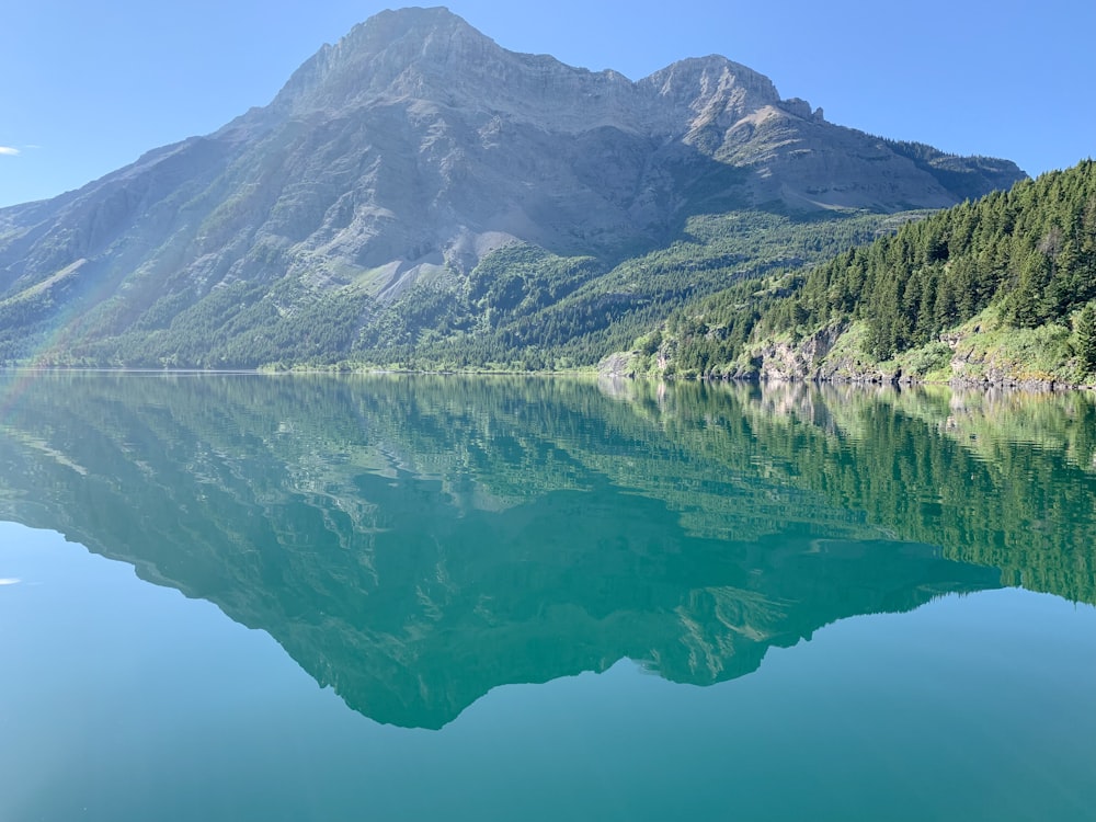 body of water viewing mountain under blue and white sky during daytime