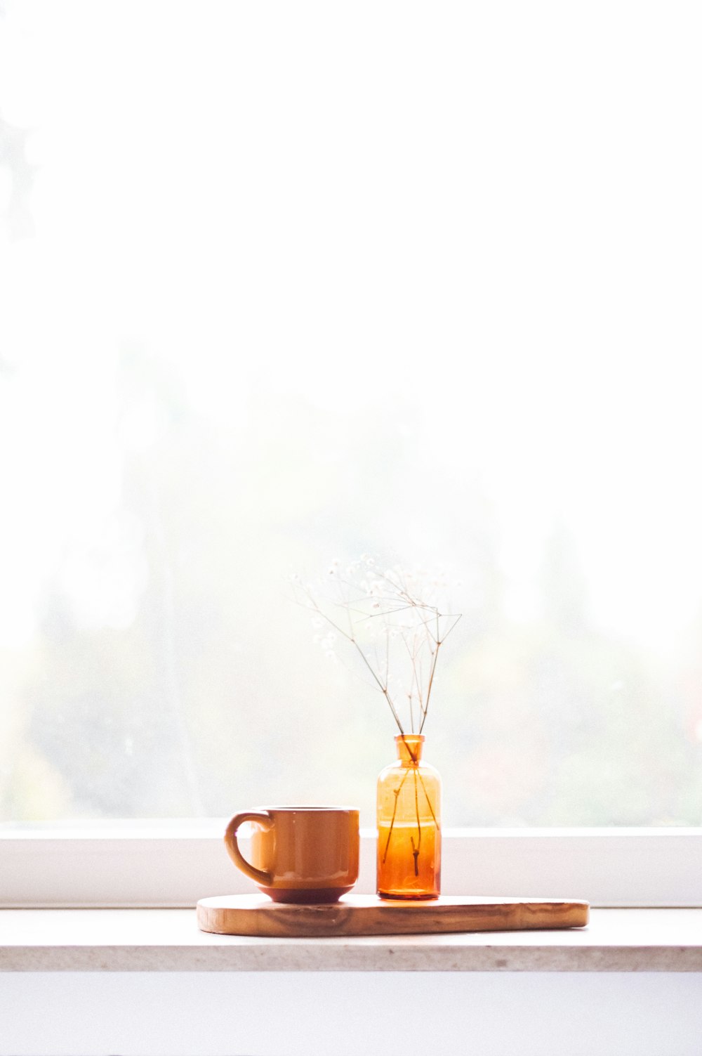 brown mug beside amber glass bottle on round brown slab