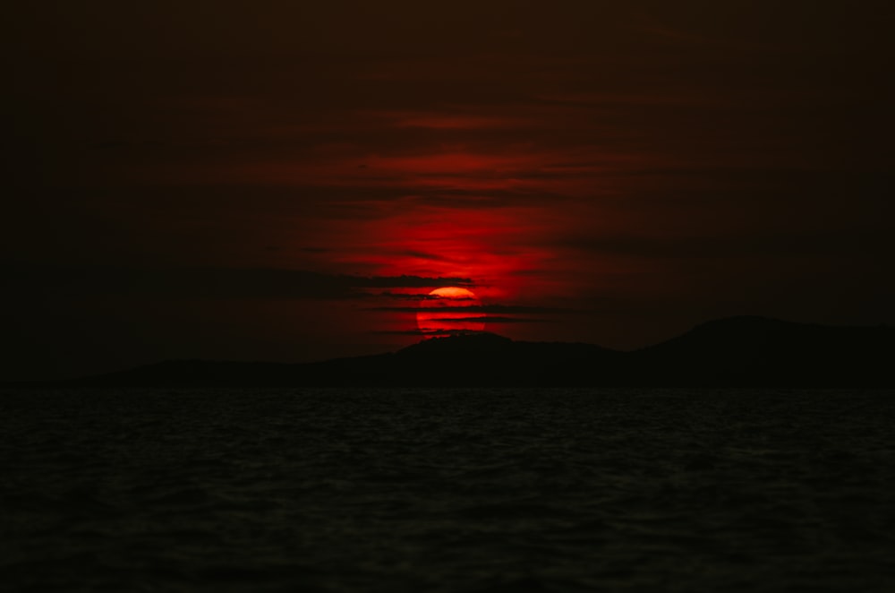 the sun is setting over the horizon of a body of water