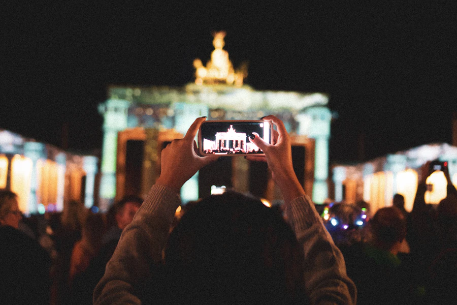 A person holding up a smartphone in a crowded public square at night, a reminder to choose busy public places for a first meeting