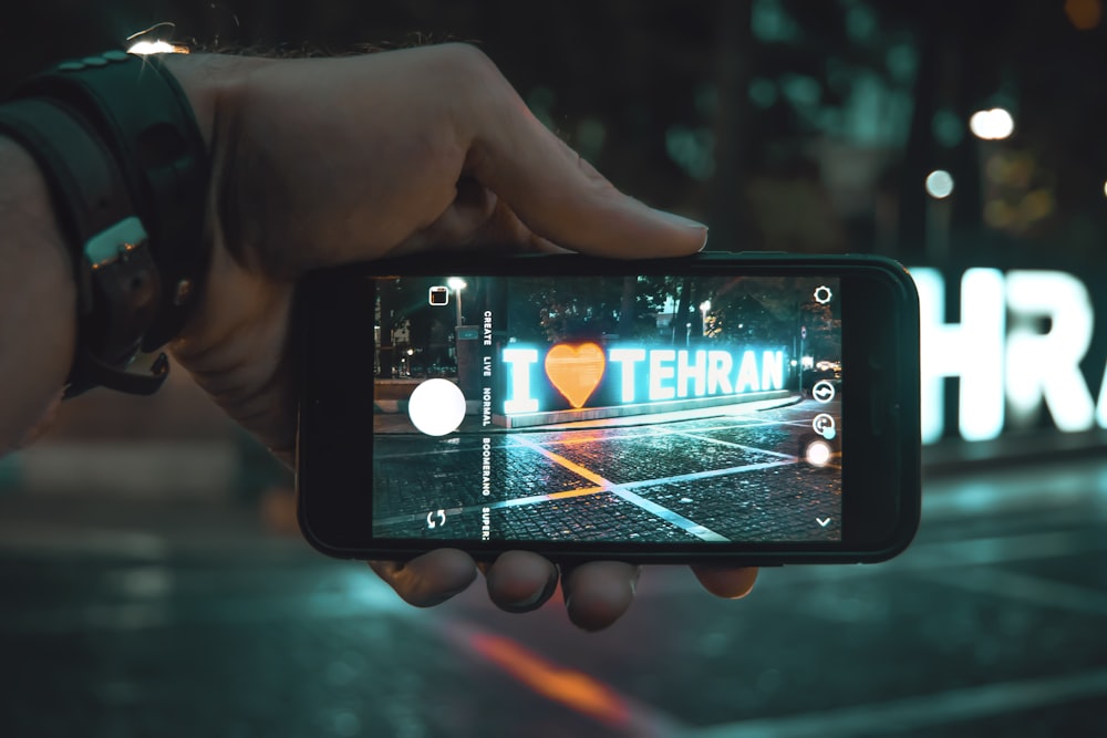 smartphone displaying camera with i love tehran lighted standee