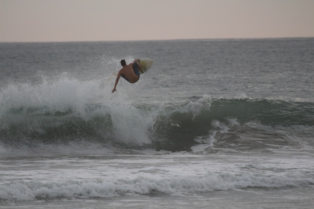 person doing a surfer stunt on waves under grya skies