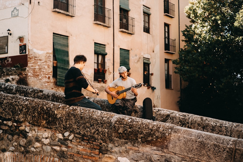 two men plays guitar and violin at the pathway