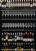 Shelves display rows of wine bottles and neatly arranged wine glasses. Various wine labels are visible, showcasing a diverse selection of bottles.