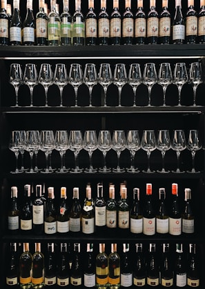 Shelves display rows of wine bottles and neatly arranged wine glasses. Various wine labels are visible, showcasing a diverse selection of bottles.